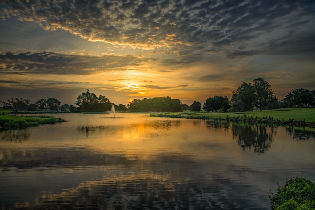 Couse greens with clouds hanging above during sunset