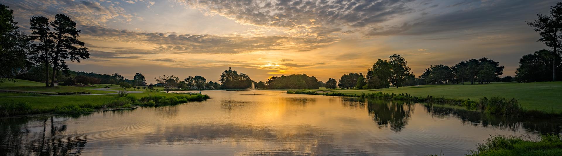 View of course greens over a lake at sunset